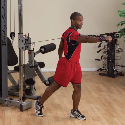 A person using the Body-Solid Pro Dual Cable Column Machine DPCCSF, performing a cable exercise with one arm extended, in a gym setting.