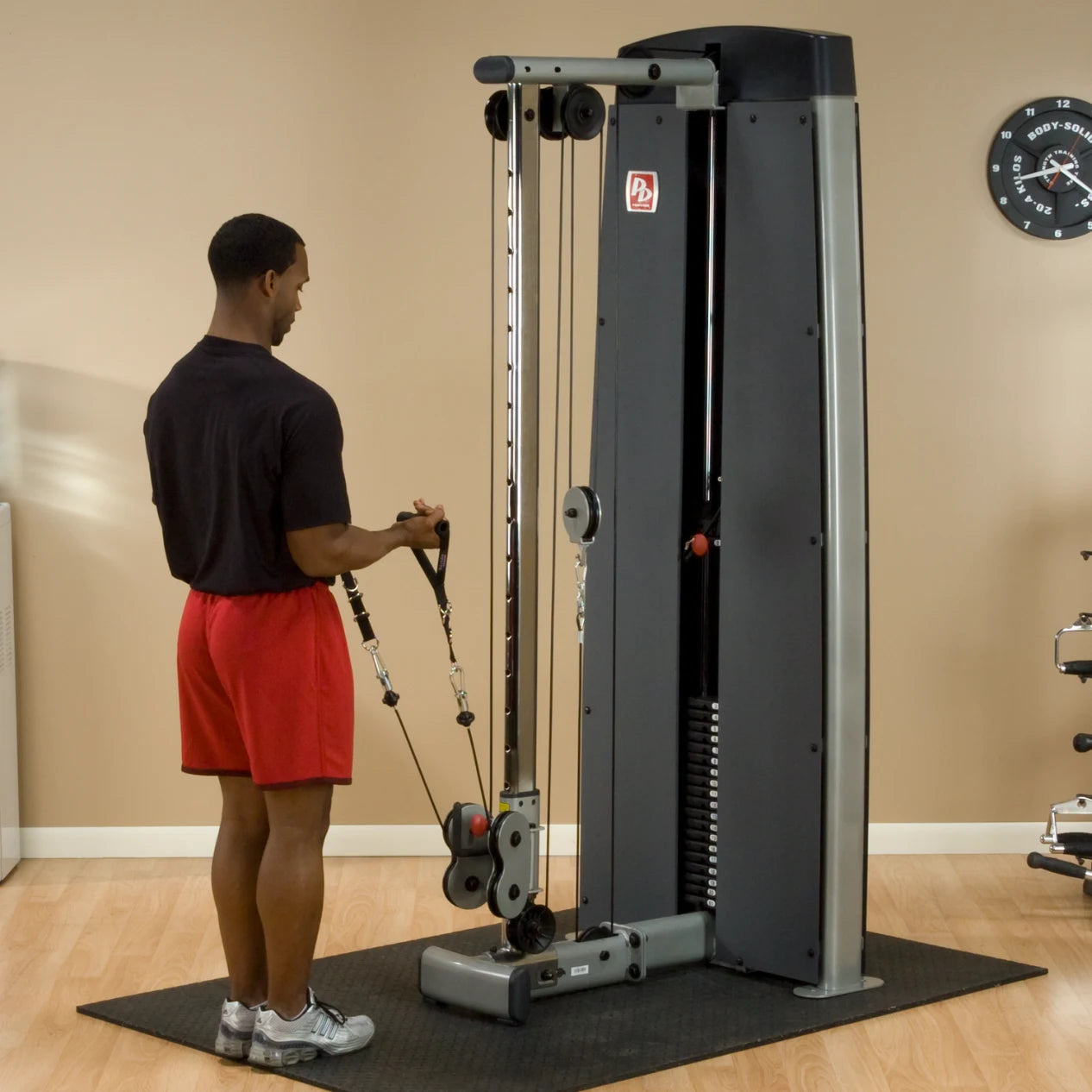 A man using the Body-Solid Pro Dual Cable Column Machine DPCCSF in a gym setting, performing an exercise with cables attached to the machine.