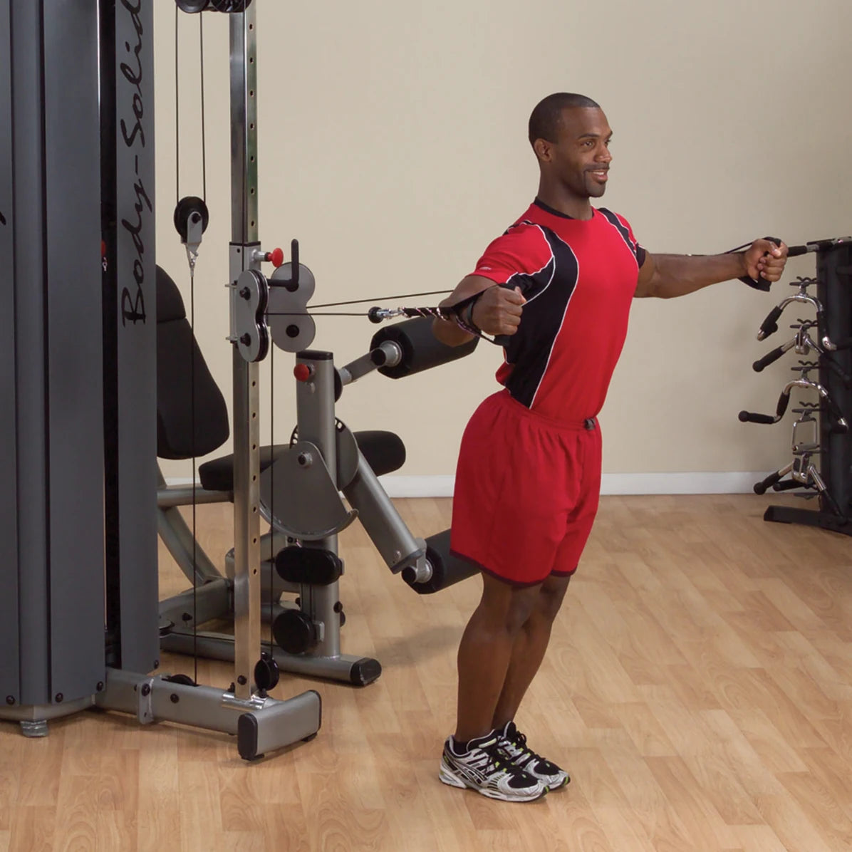 A person performing an exercise using the Body-Solid Pro Dual Cable Column Machine DPCCSF in a gym setting, demonstrating proper form with cables extended.