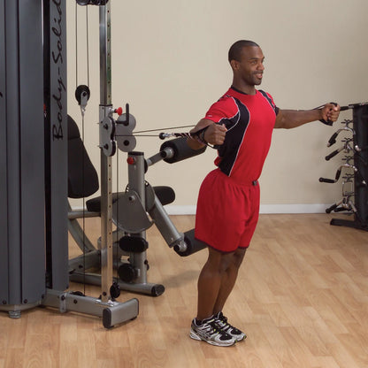 A person performing an exercise using the Body-Solid Pro Dual Cable Column Machine DPCCSF in a gym setting, demonstrating proper form with cables extended.