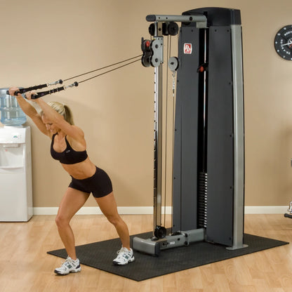 A woman performs an exercise using the Body-Solid Pro Dual Cable Column Machine DPCCSF in a gym setting, showcasing her strength and fitness.