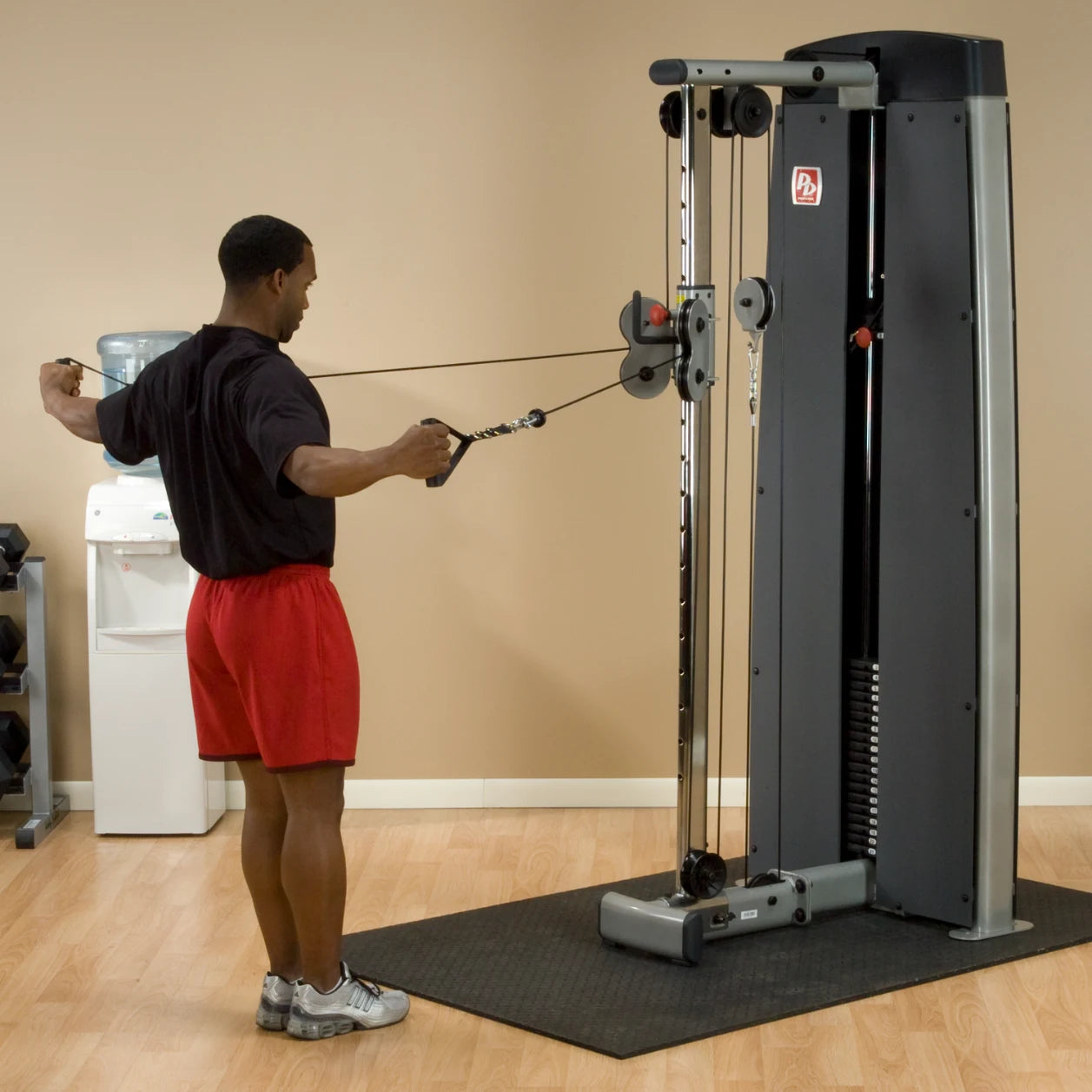 A person using the Body-Solid Pro Dual Cable Column Machine DPCCSF, performing a cable exercise in a gym setting.