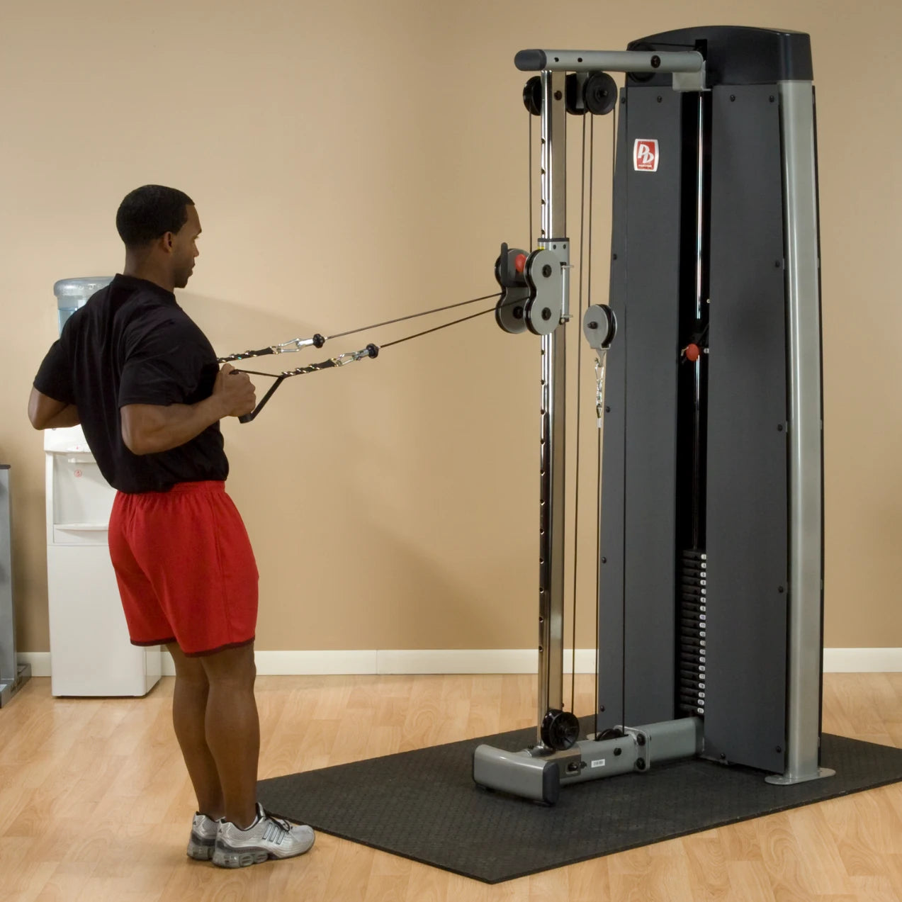 A person using the Body-Solid Pro Dual Cable Column Machine DPCCSF in a gym setting, performing a cable exercise with adjustable pulleys.