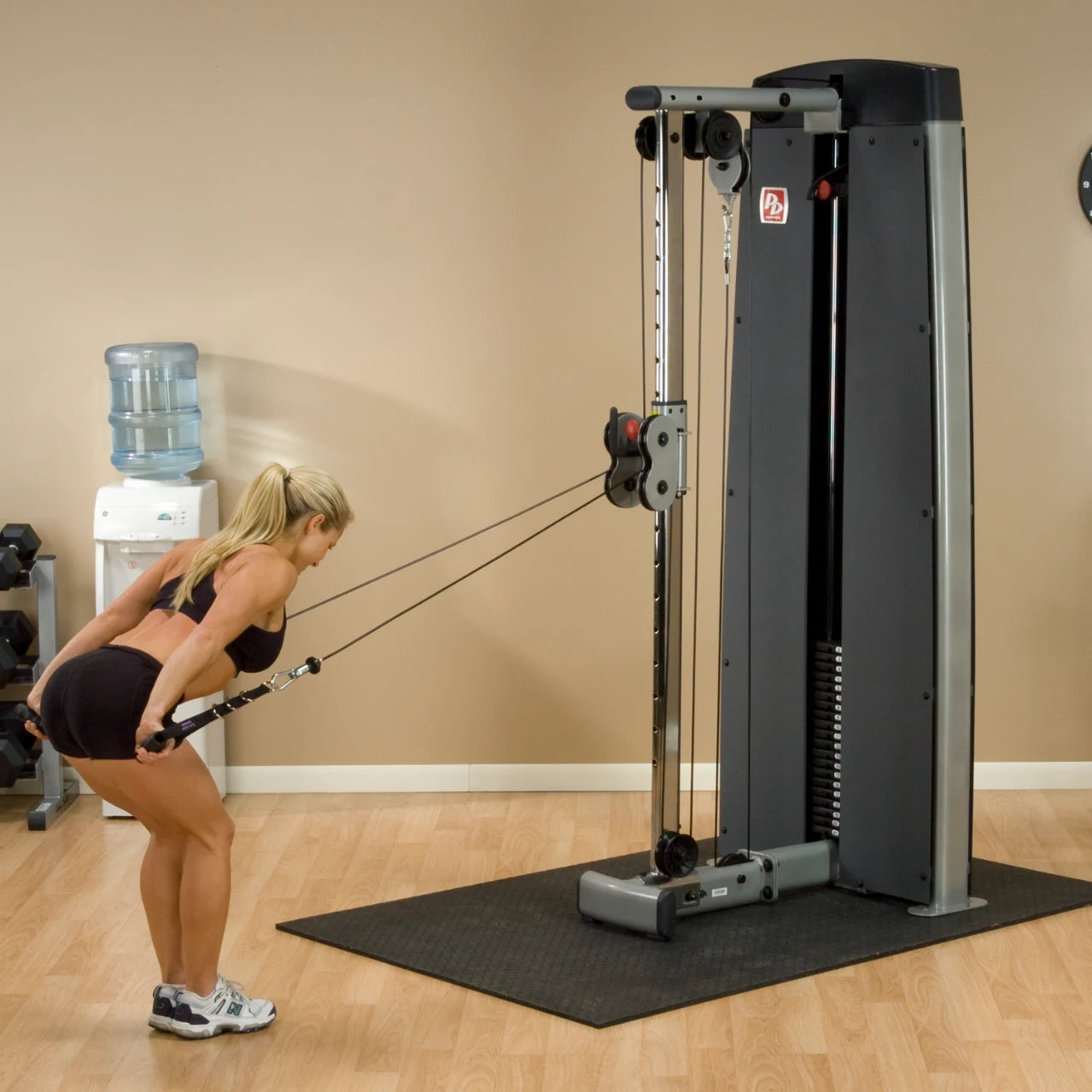 Woman performing an exercise using the Body-Solid Pro Dual Cable Column Machine DPCCSF in a gym setting.
