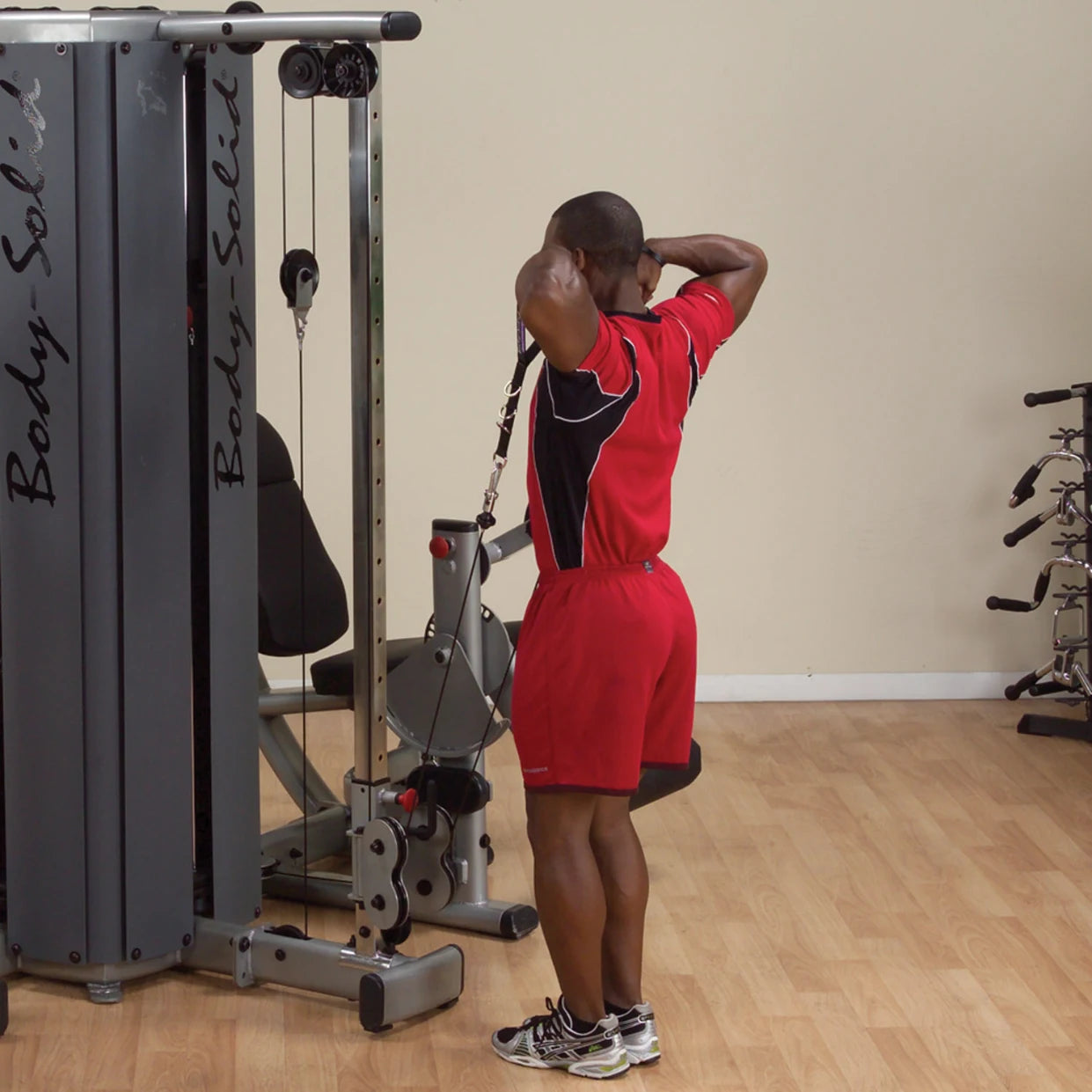 Person using the Body-Solid Pro Dual Cable Column Machine DPCCSF for an exercise in a gym setting.