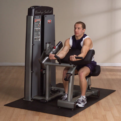 Individual using the Body-Solid Pro Dual Bicep & Tricep Machine DBTCSF in a gym setting, performing a bicep curl exercise.