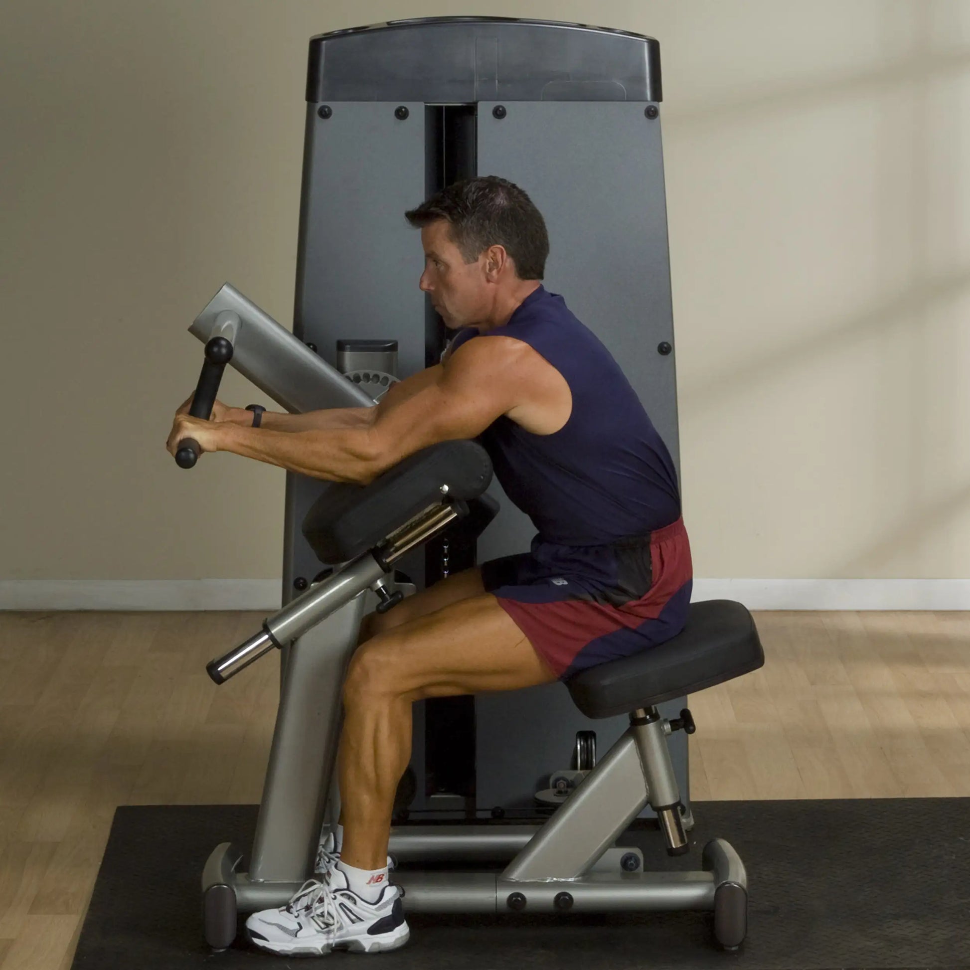 A person demonstrating the Body-Solid Pro Dual Bicep & Tricep Machine DBTCSF in a fitness setting, focusing on arm exercises.