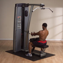 A person using the Body-Solid Pro Dual Lat & Mid Row Machine DLATSF in a fitness studio, performing a rowing exercise.