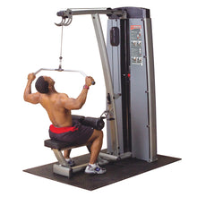 A person using the Body-Solid Pro Dual Lat & Mid Row Machine DLATSF for exercise, performing a lat pulldown while seated on the machine.