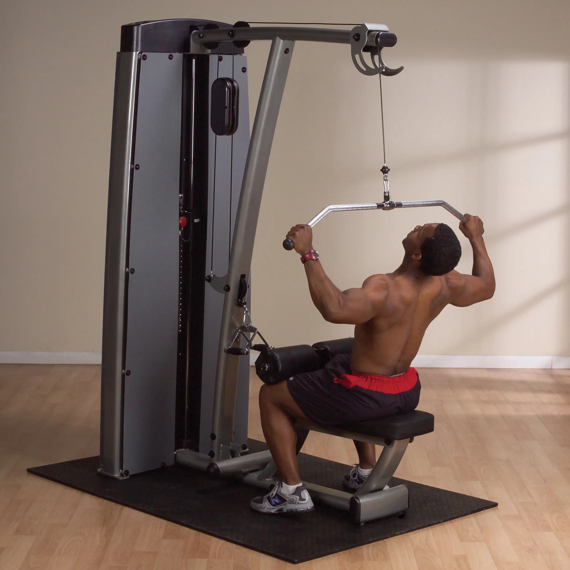 A person using the Body-Solid Pro Dual Lat & Mid Row Machine DLATSF for a lat pull-down exercise, showcasing their upper body strength in a gym setting.