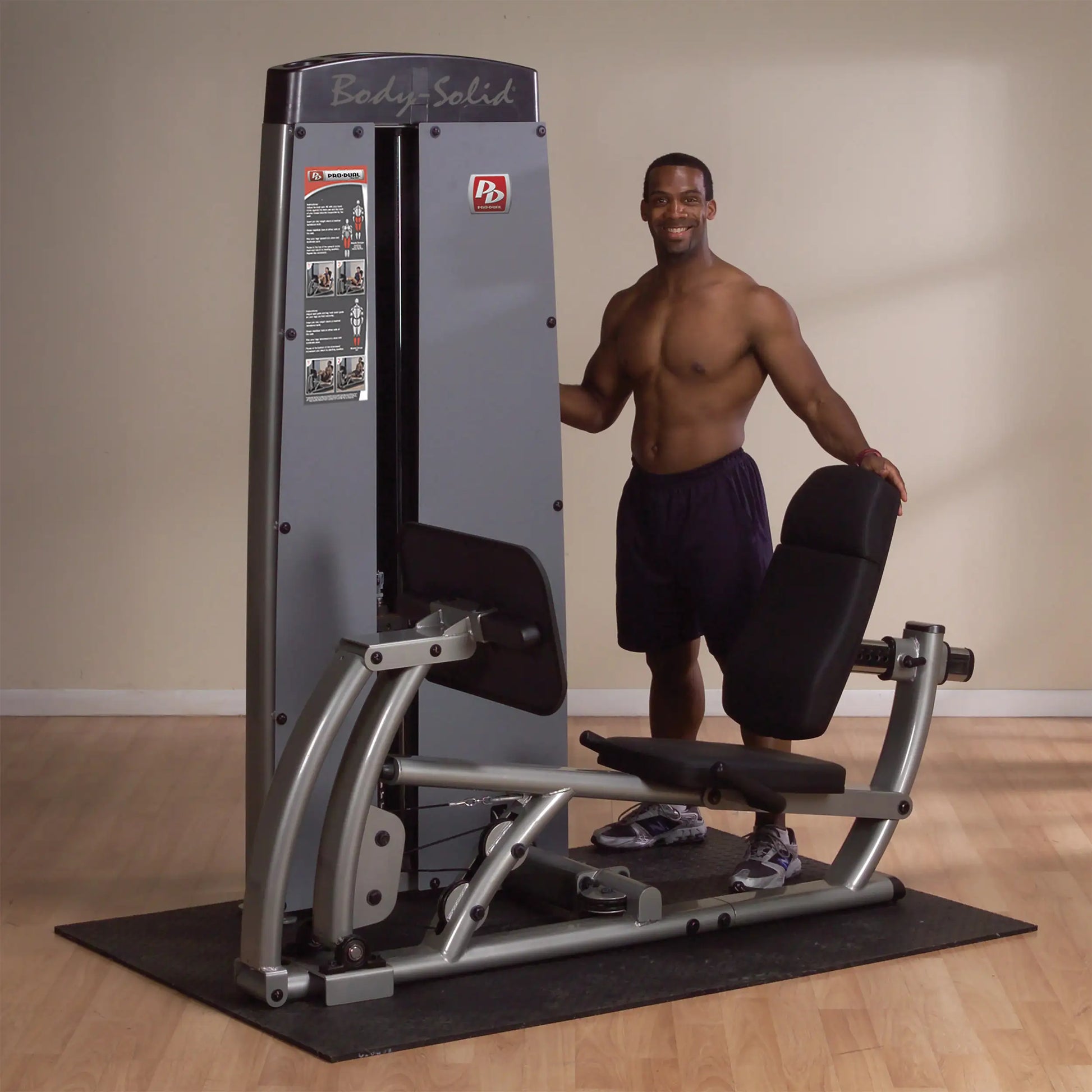 A man stands next to the Body-Solid Pro Dual Leg & Calf Press Machine DCLPSF in a gym setting, showcasing the equipment designed for leg and calf exercises.