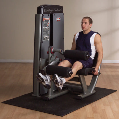 A man using the Body-Solid Pro Dual Leg Extension & Curl Machine DLECSF in a gym setting, demonstrating leg extension exercise.