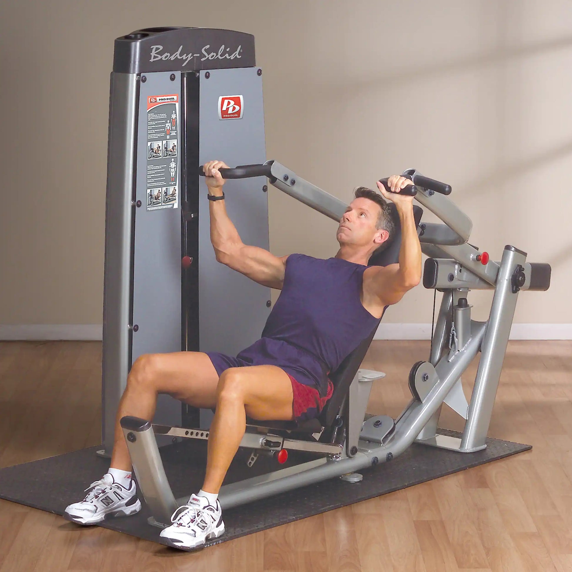 A man using the Body-Solid Pro Dual Multi-Press Machine DPRSSF for strength training, focusing on upper body exercises in a well-lit gym setting.