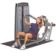 A man using the Body-Solid Pro Dual Multi-Press Machine DPRSSF for strength training, performing a press exercise while seated.