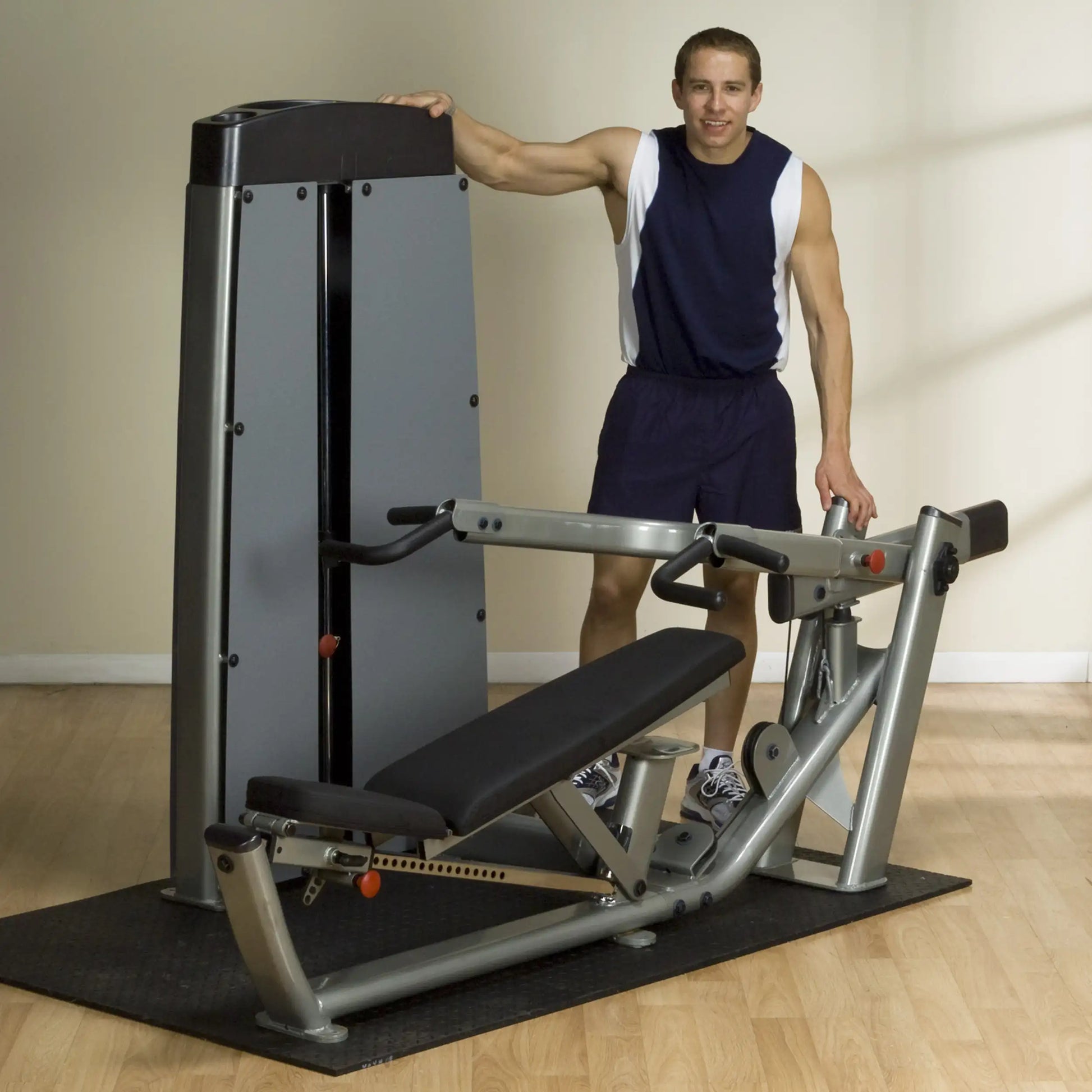 A person standing next to a Body-Solid Pro Dual Multi-Press Machine DPRSSF in a gym setting, showcasing the equipment's design and features.