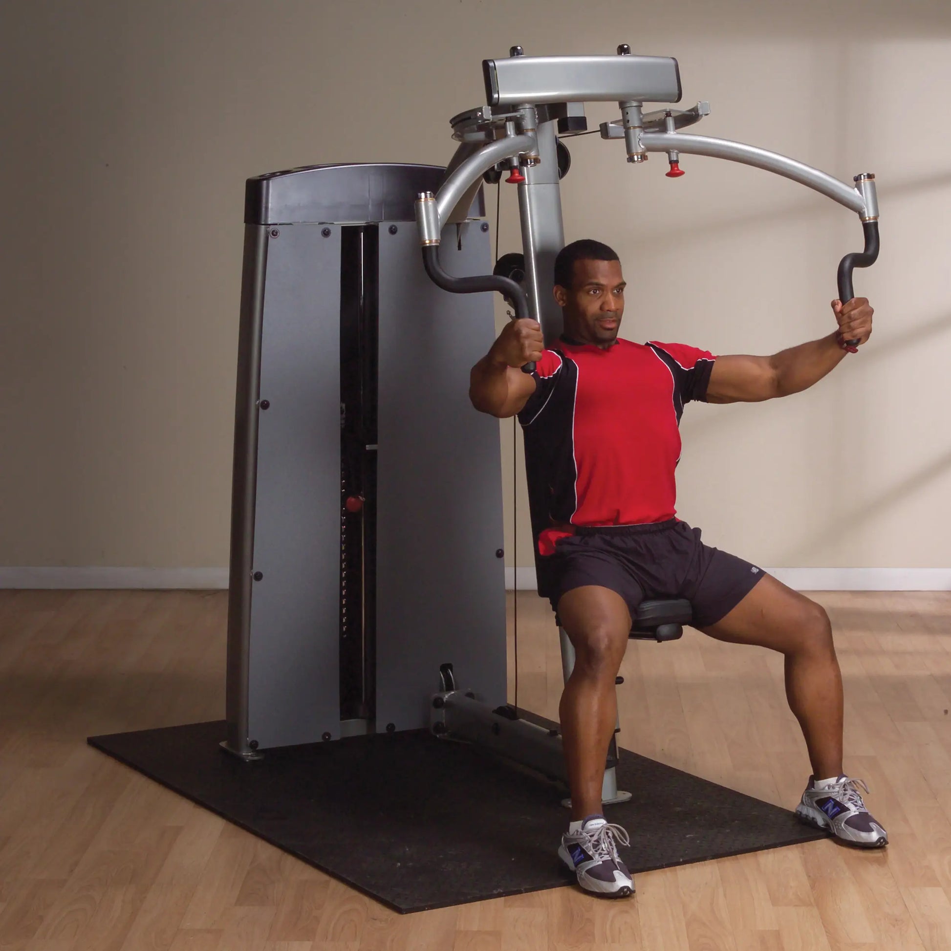 A man using the Body-Solid Pro Dual Pec & Rear Delt Machine DPECSF, seated and engaging in a workout, with his arms positioned to perform a chest exercise.