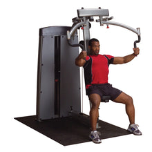 A person using the Body-Solid Pro Dual Pec & Rear Delt Machine DPECSF, seated and performing a chest exercise, with a focused expression, in a gym setting.