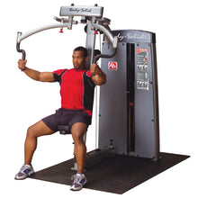 A person using the Body-Solid Pro Dual Pec & Rear Delt Machine DPECSF, performing a chest exercise while seated.
