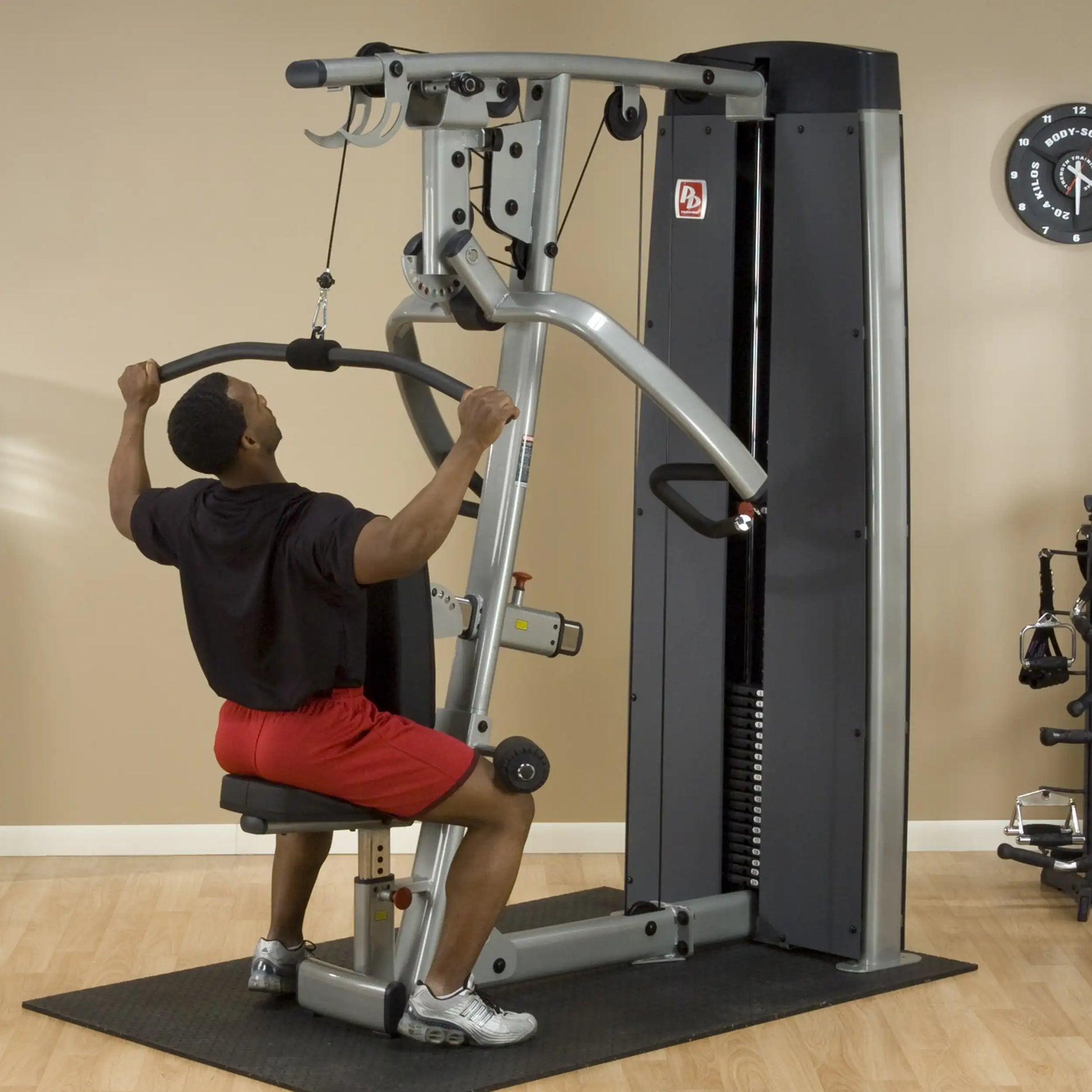 A person using the Body-Solid Pro Dual Vertical Press & Lat Machine DPLSSF for strength training, performing a lat pulldown exercise in a gym setting.
