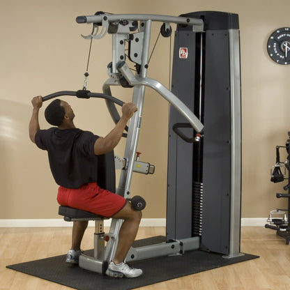 A person using the Body-Solid Pro Dual Vertical Press & Lat Machine DPLSSF for strength training, performing a lat pulldown exercise in a gym setting.
