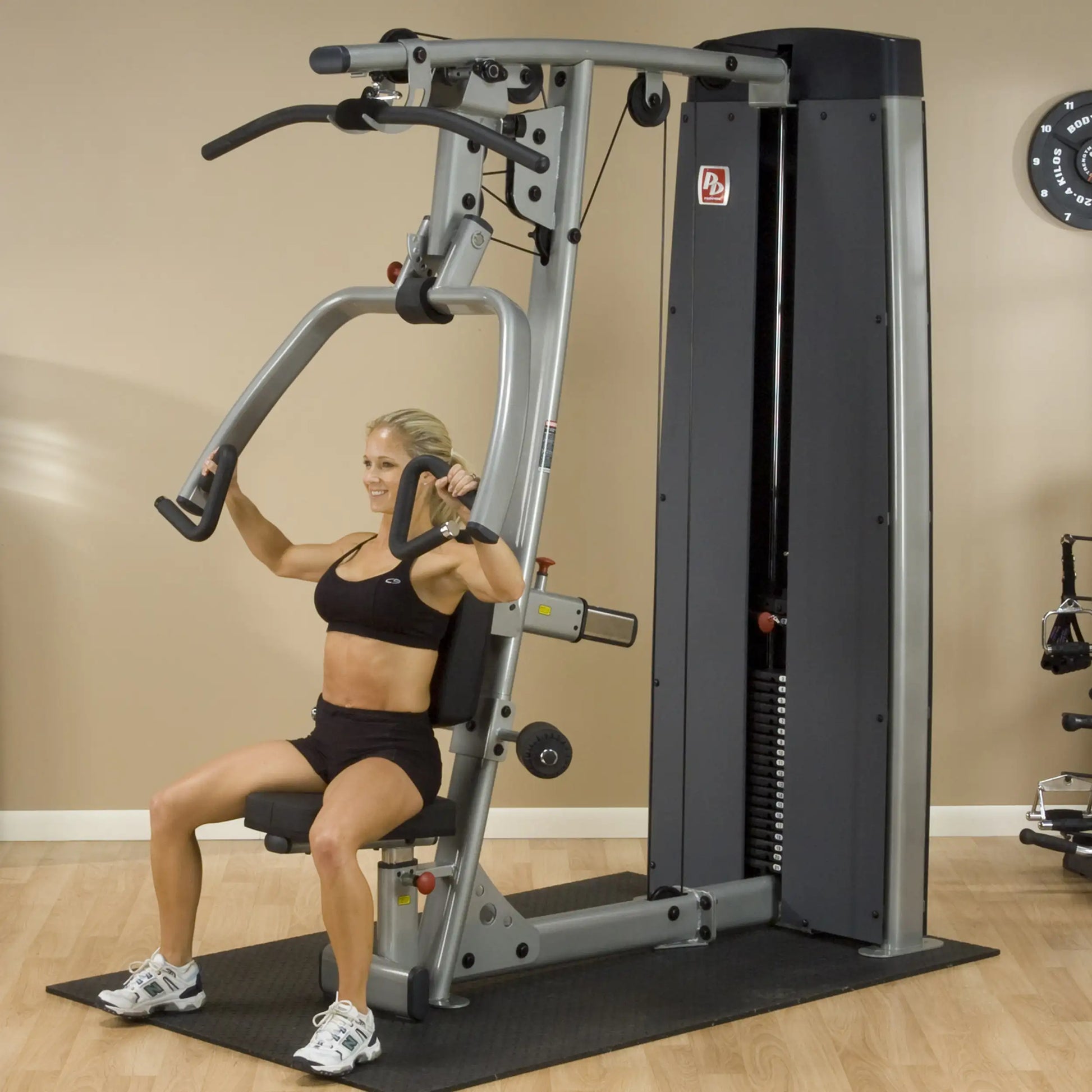 A woman using the Body-Solid Pro Dual Vertical Press & Lat Machine DPLSSF for strength training, demonstrating proper form while seated.