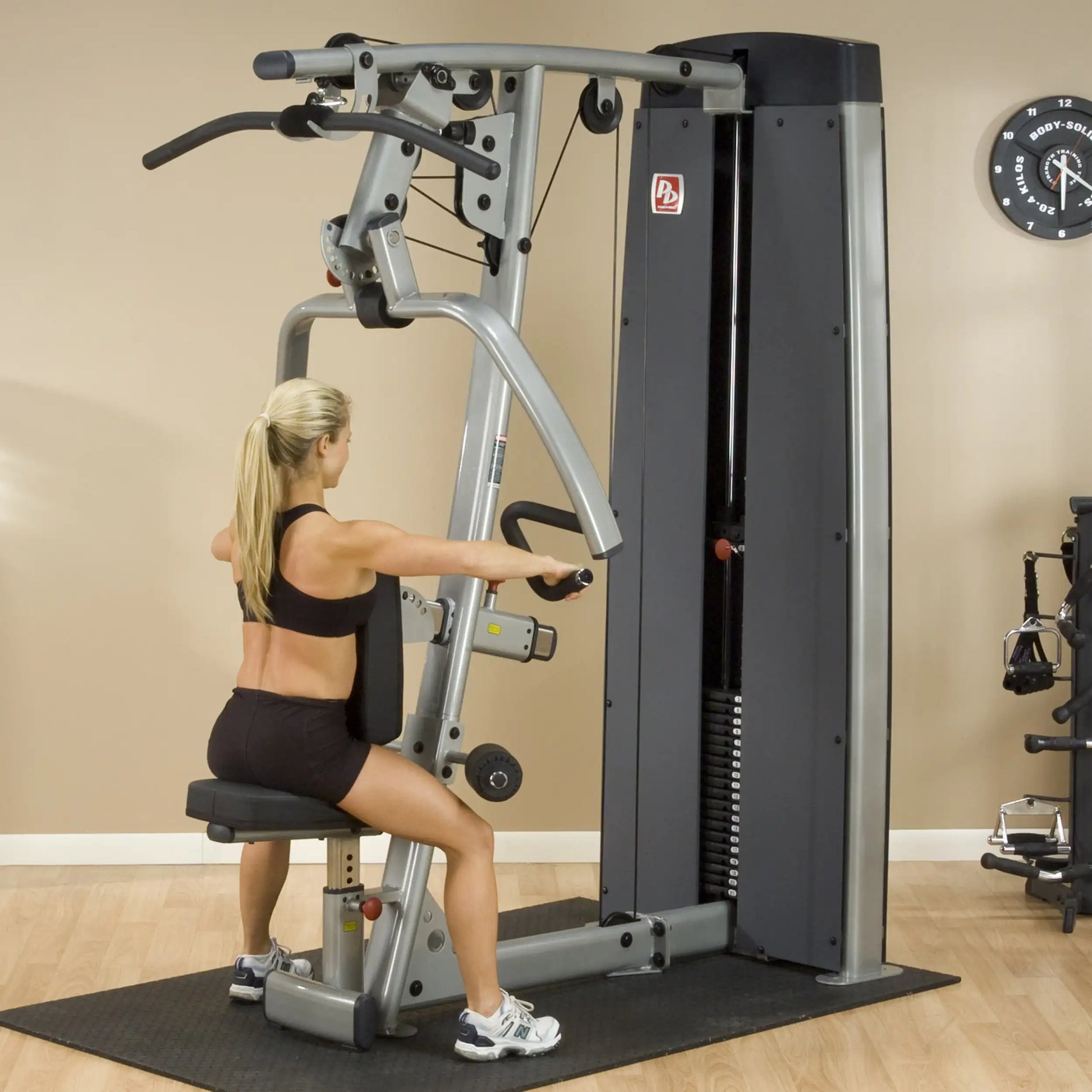 A woman using the Body-Solid Pro Dual Vertical Press & Lat Machine DPLSSF in a gym setting, demonstrating strength training exercises.