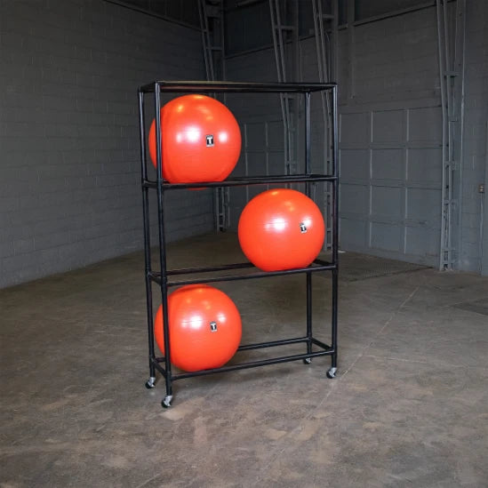Orange gym balls on a black metal rack in a spacious warehouse.
