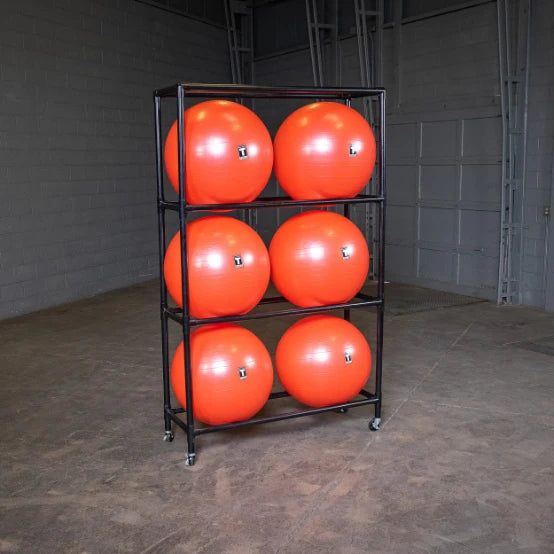 Six orange exercise balls on a black rack in a gym storage room.