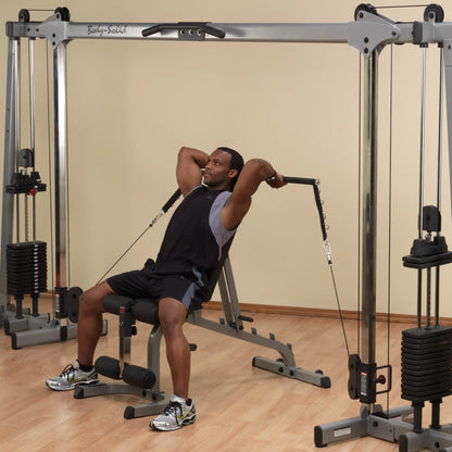 Man using Body-Solid home gym for tricep exercises, wearing black and gray workout attire.