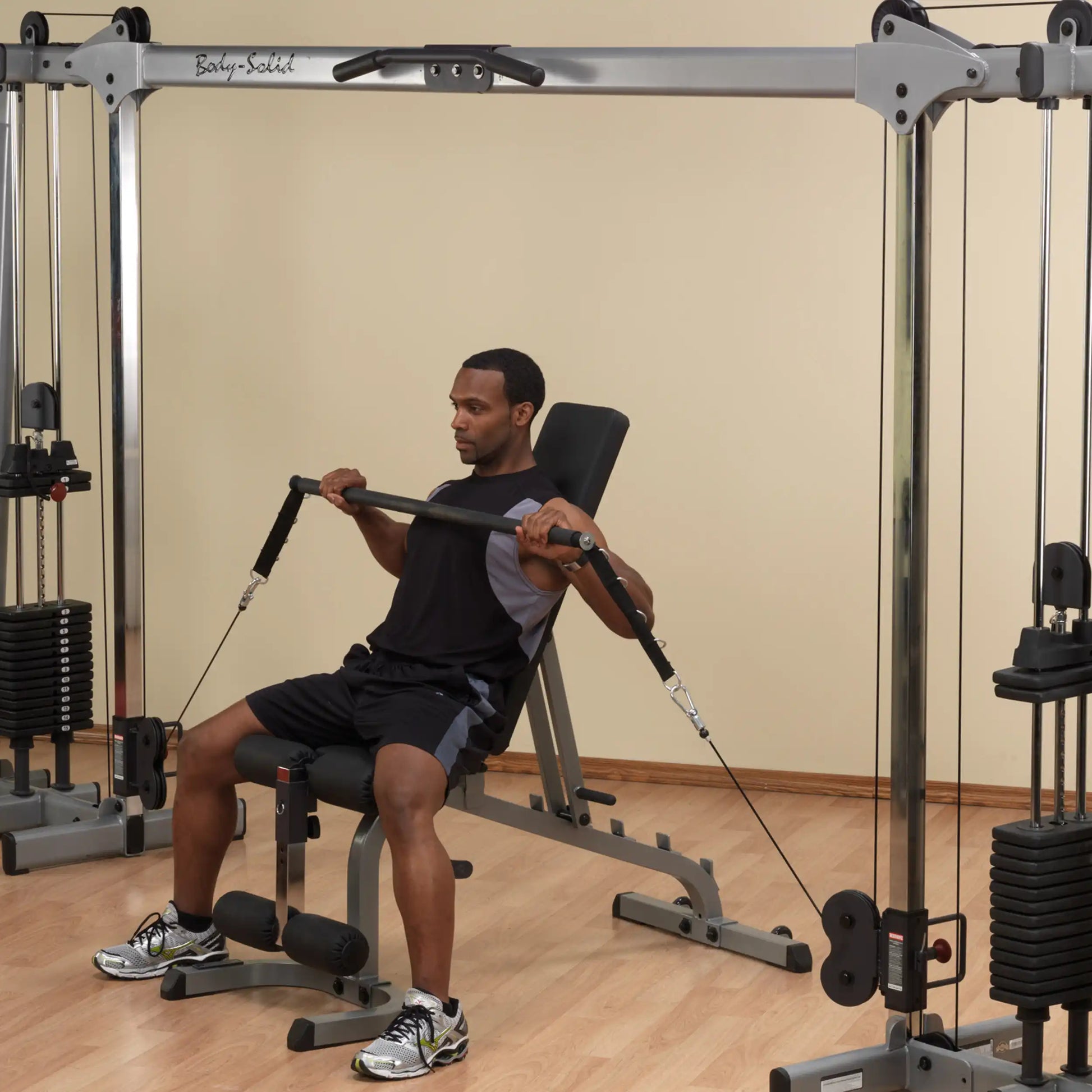 Man using Body-Solid home gym machine with cable crossover for strength training.