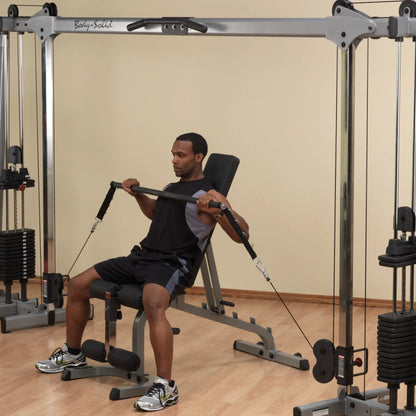 Man using Body-Solid home gym machine with cable crossover for strength training.