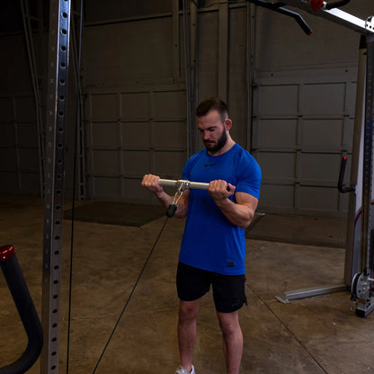 Man in blue shirt using cable machine for bicep curls in a gym.