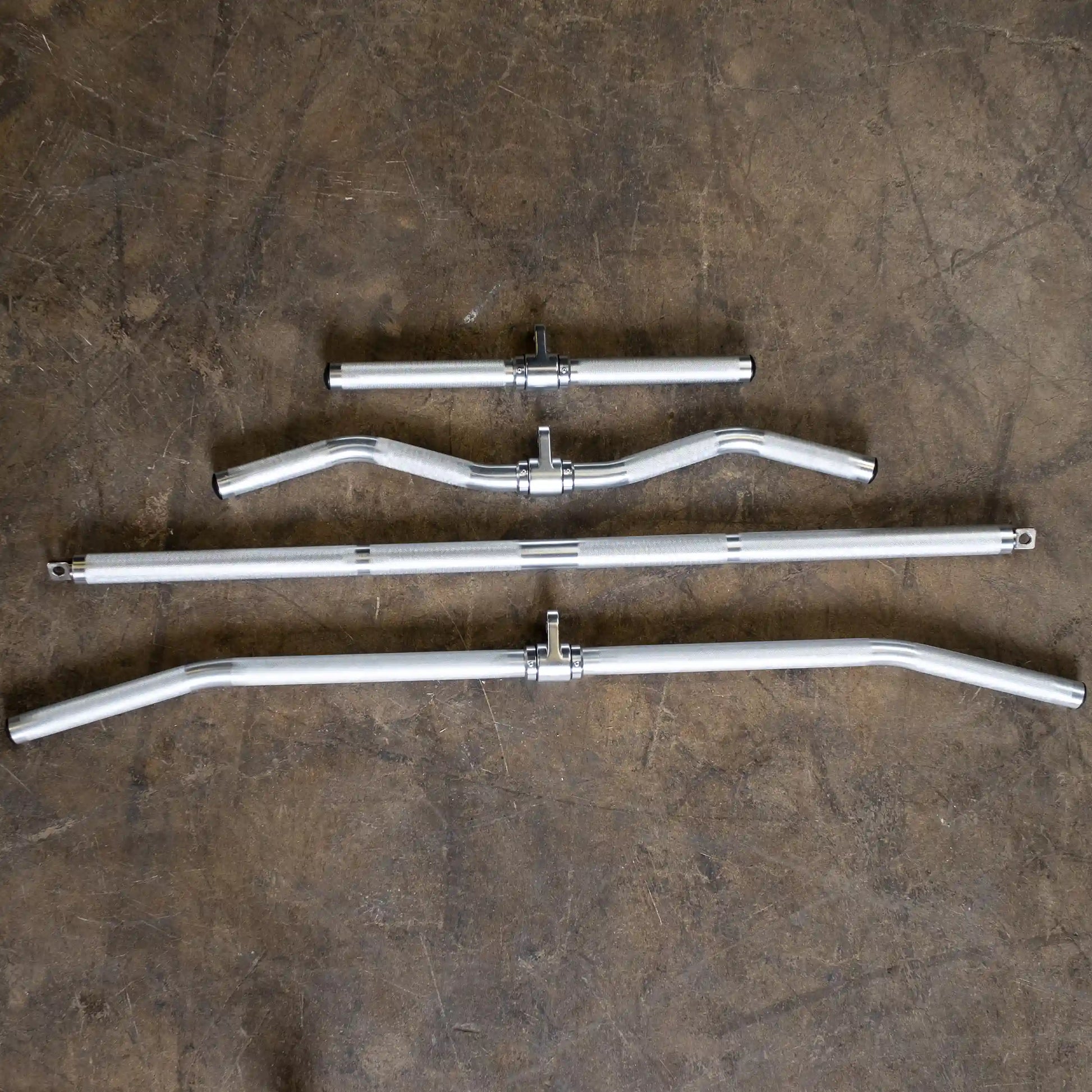 Four silver handlebar styles for bicycles on a concrete floor.