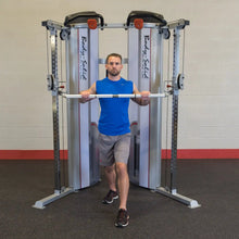 Man performing cable chest press on Body-Solid machine in gym, wearing blue shirt and gray shorts.