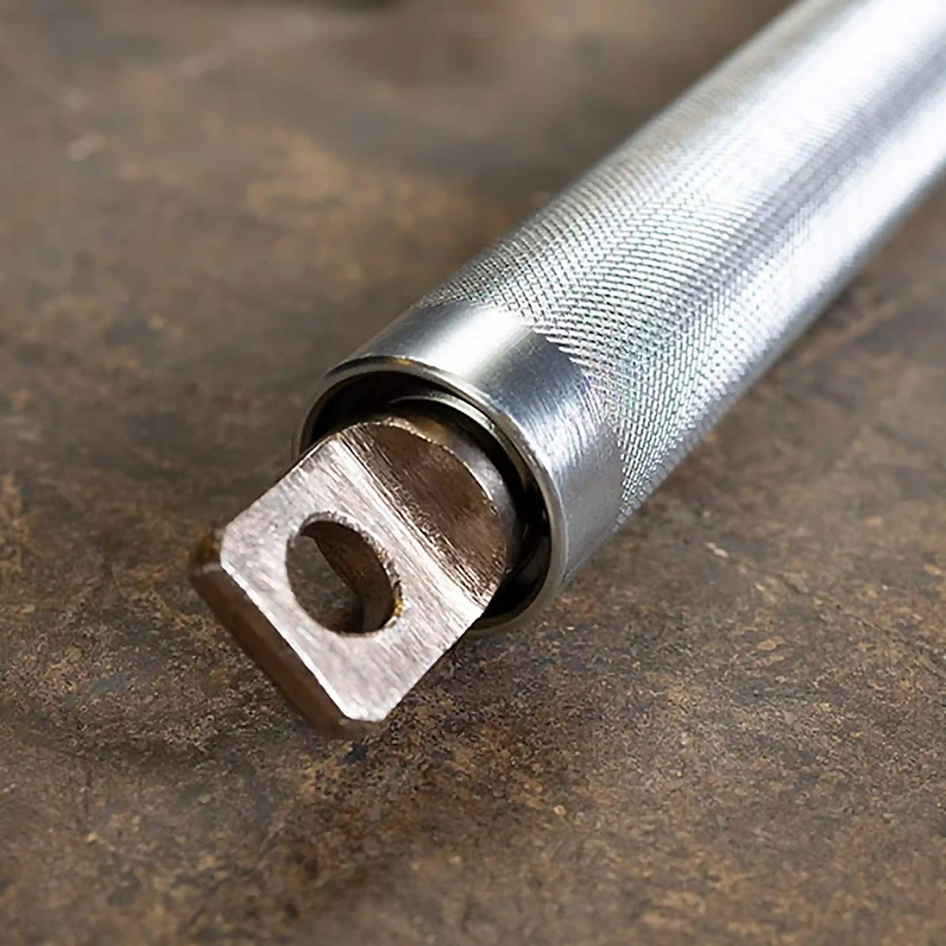 Knurled stainless steel barbell handle with rotating sleeve for secure grip.
