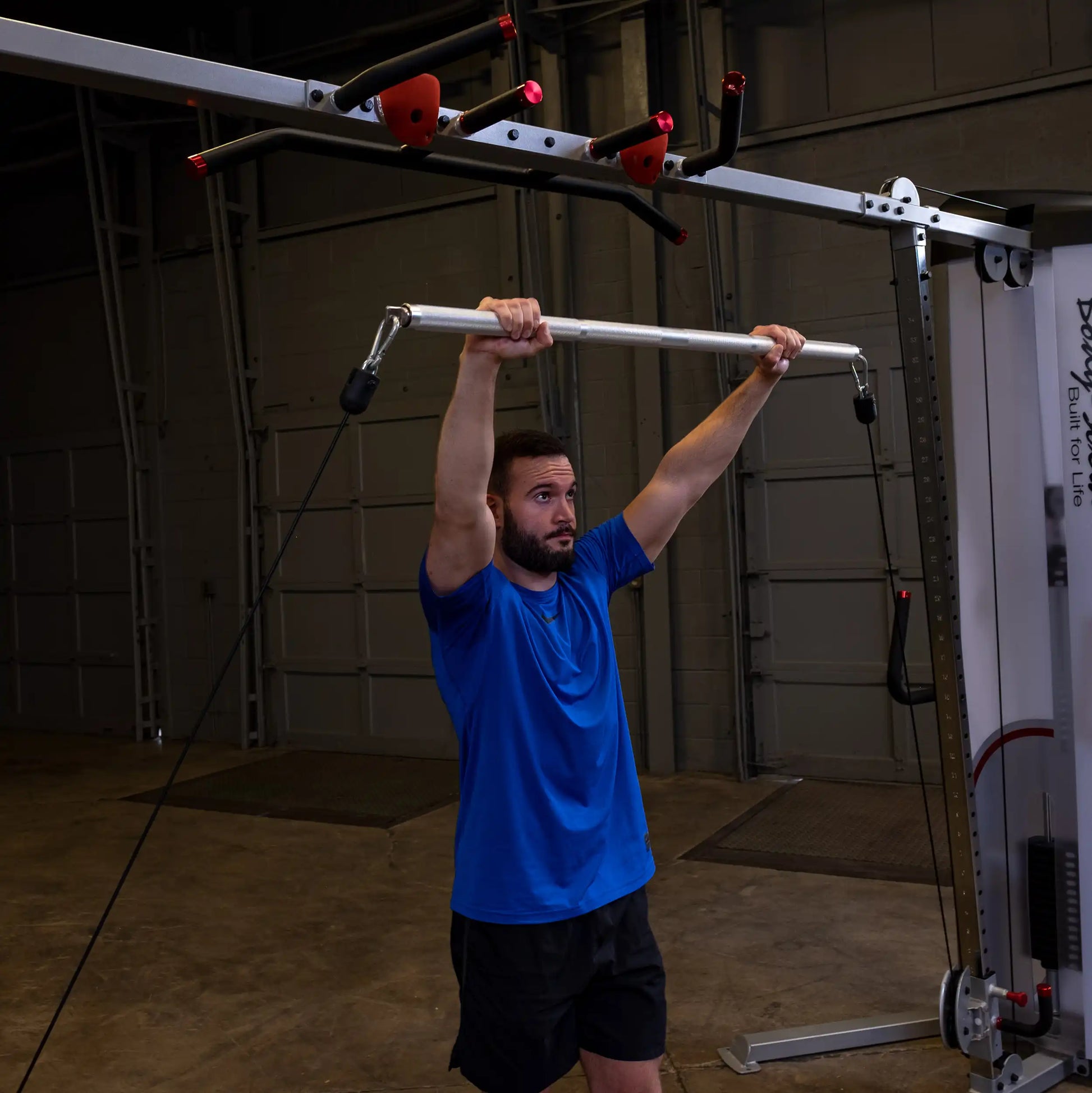 Man in blue shirt using cable machine for strength training.