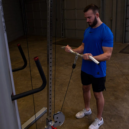 Man in blue shirt using cable machine for bicep curls in gym.