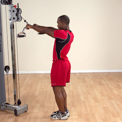 Man in red workout attire using a cable machine for tricep exercises in a gym.