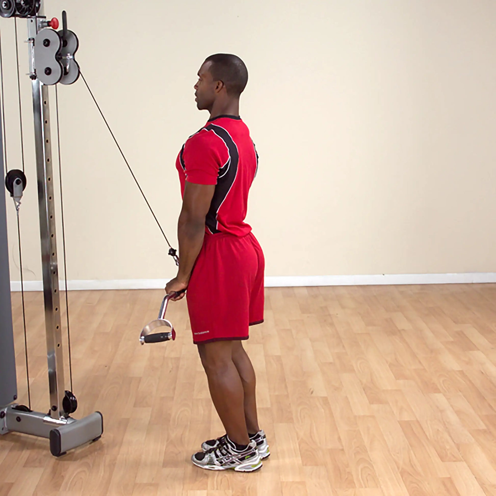 Man in red athletic outfit performing tricep pushdown on cable machine.