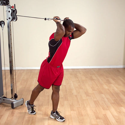 Man performing tricep cable extension in red sportswear at gym.