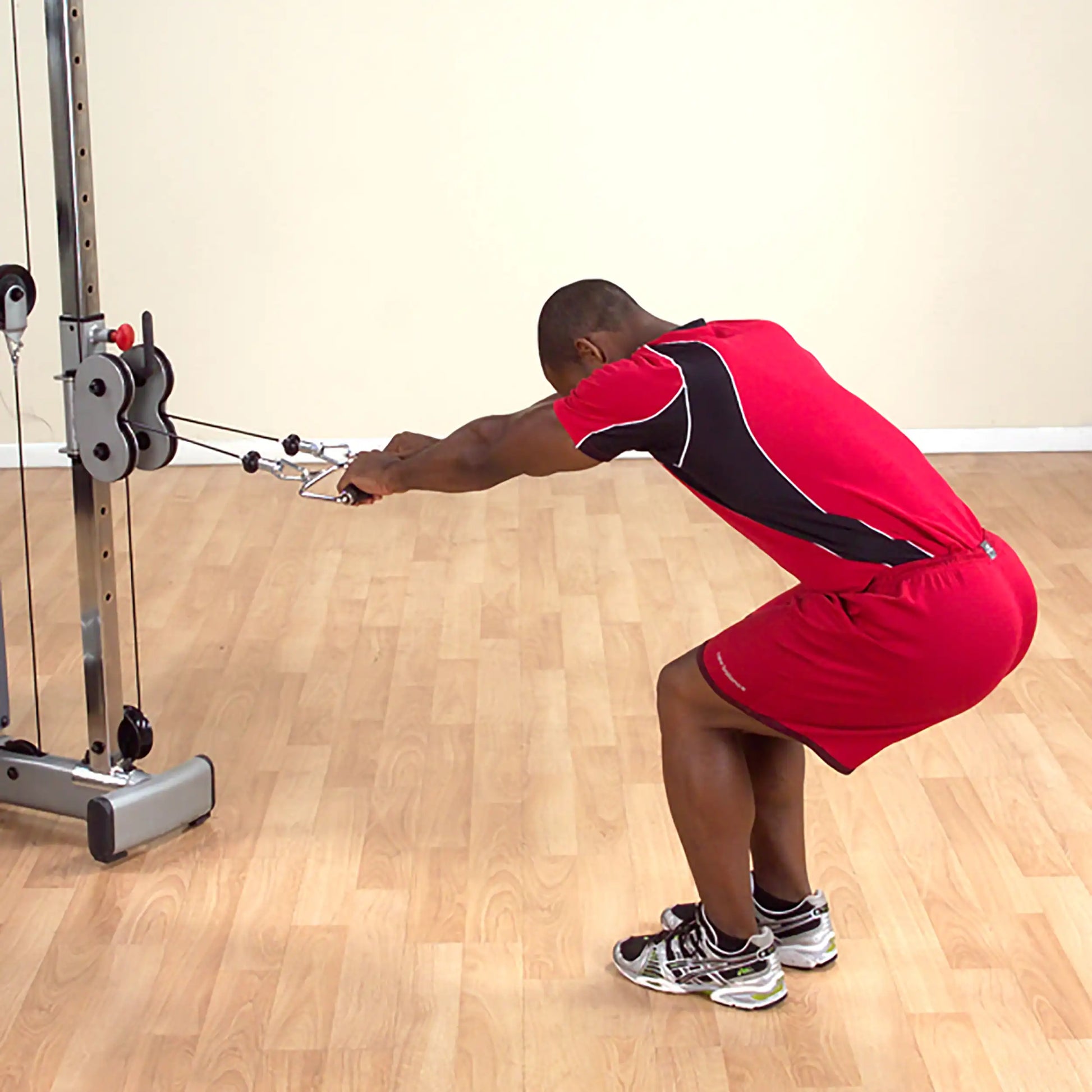 Man performing cable pull-through exercise in red athletic wear.