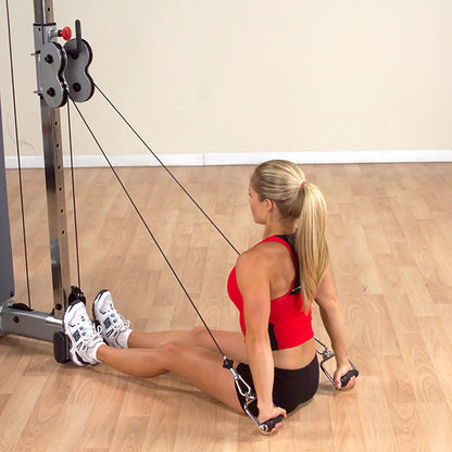 Woman in red top using cable row machine on wood floor for strength training.