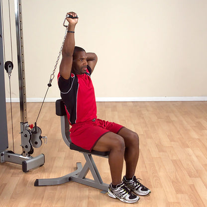 Man in red athletic outfit using a cable machine for tricep exercise in a gym.