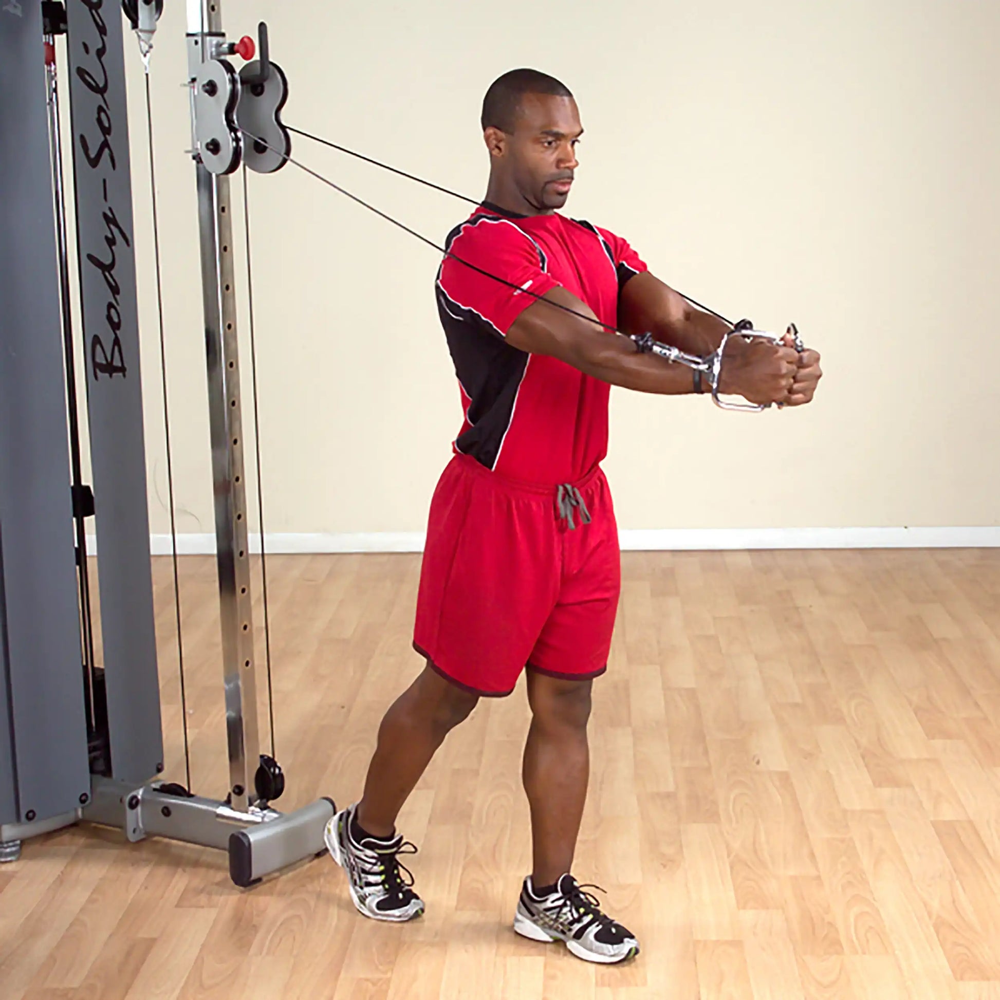 Man in red athletic wear using Body-Solid cable machine for chest workout.