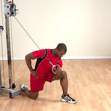 Man in red shirt performing single-arm cable row on gym machine.