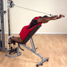 Man using Body-Solid cable machine for upper body workout on incline bench, wearing red athletic outfit.