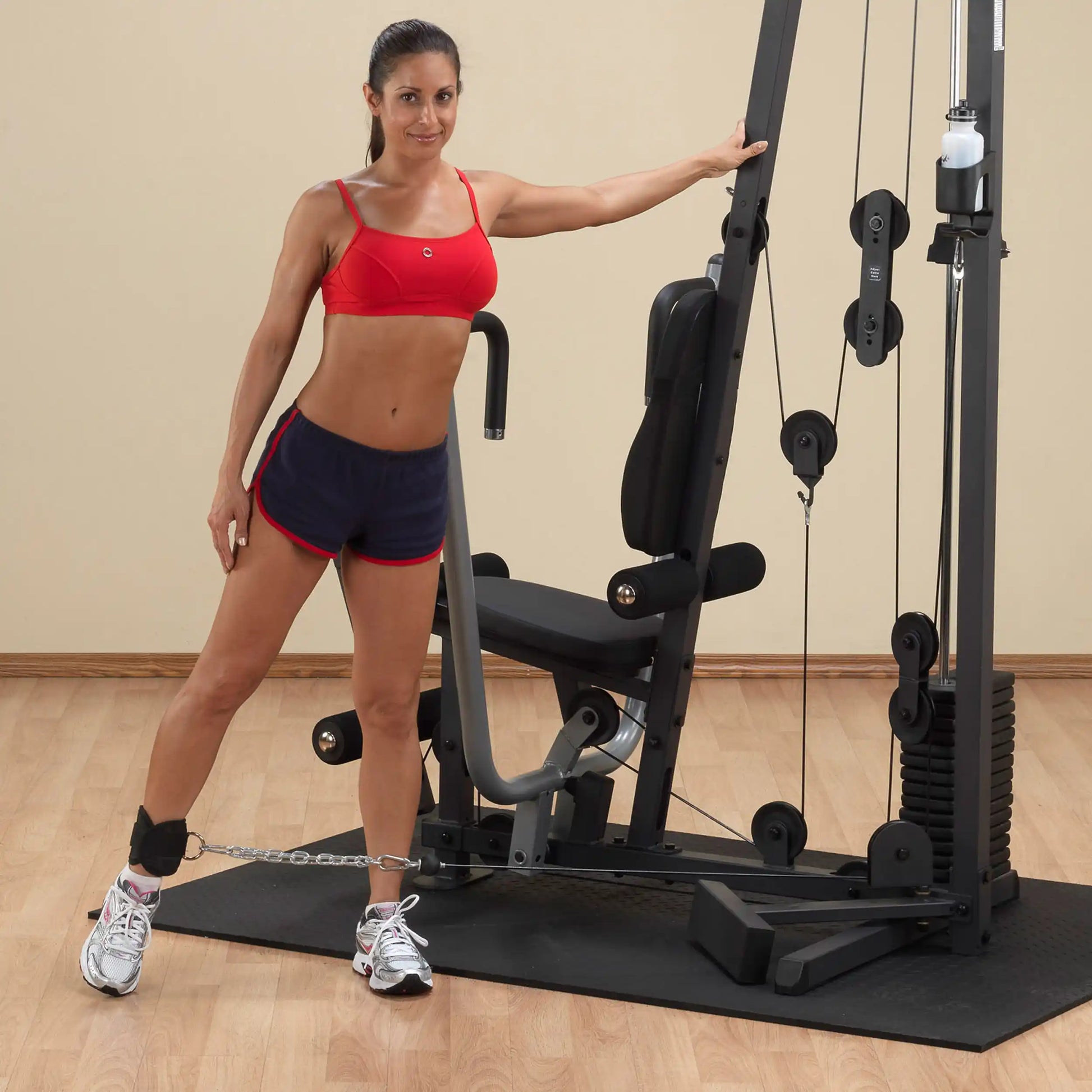 Woman in red sports bra using a leg machine in a home gym.