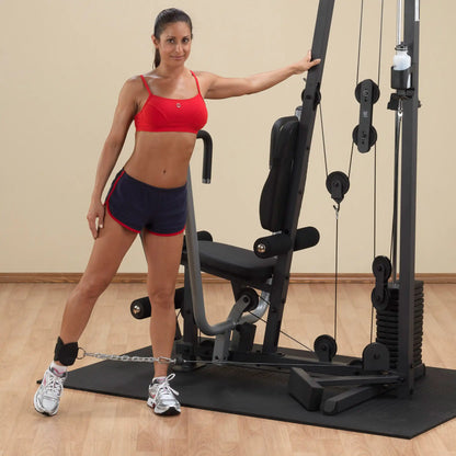 Woman in red sports bra using a leg machine in a home gym.