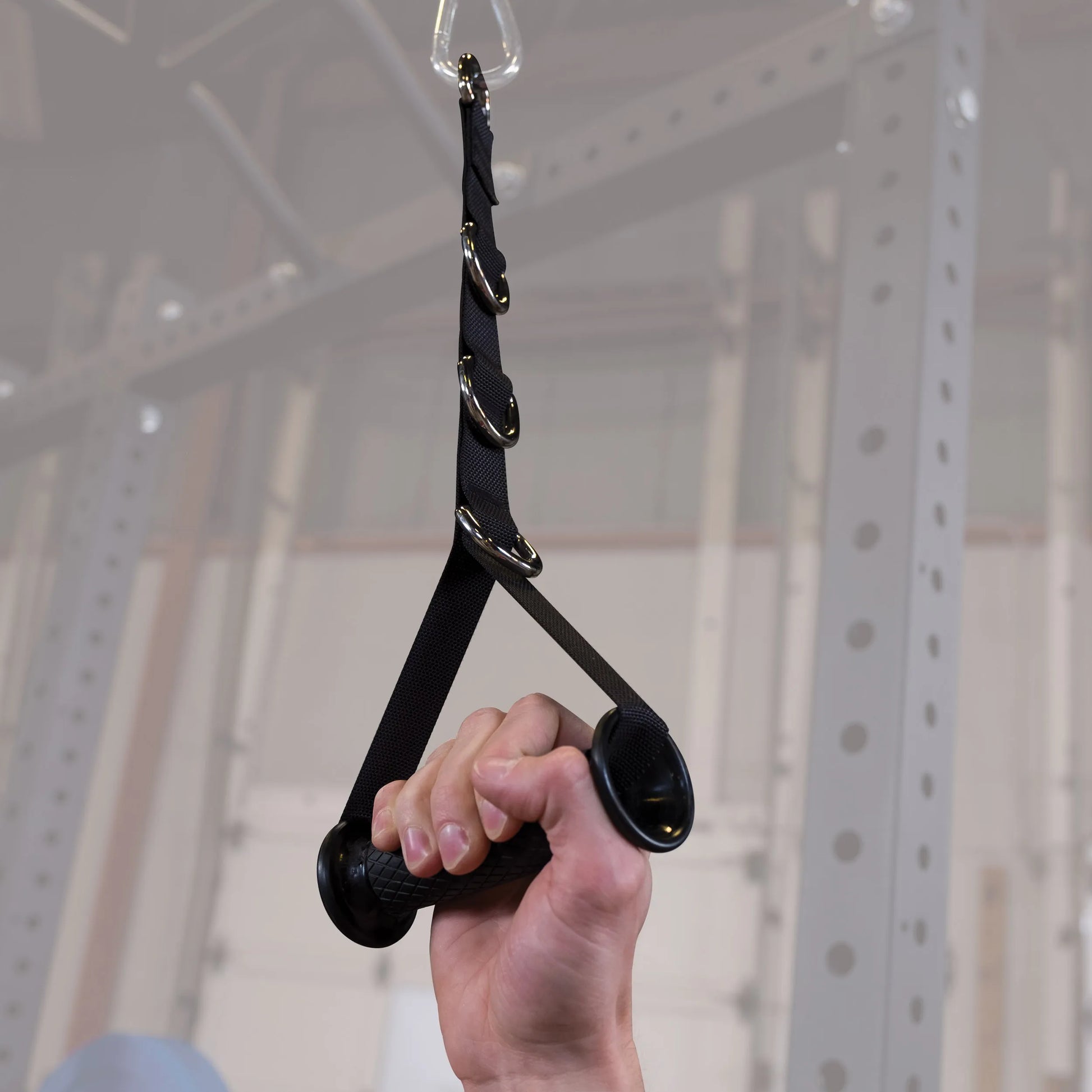 Black adjustable exercise handle with metal rings for gym equipment.