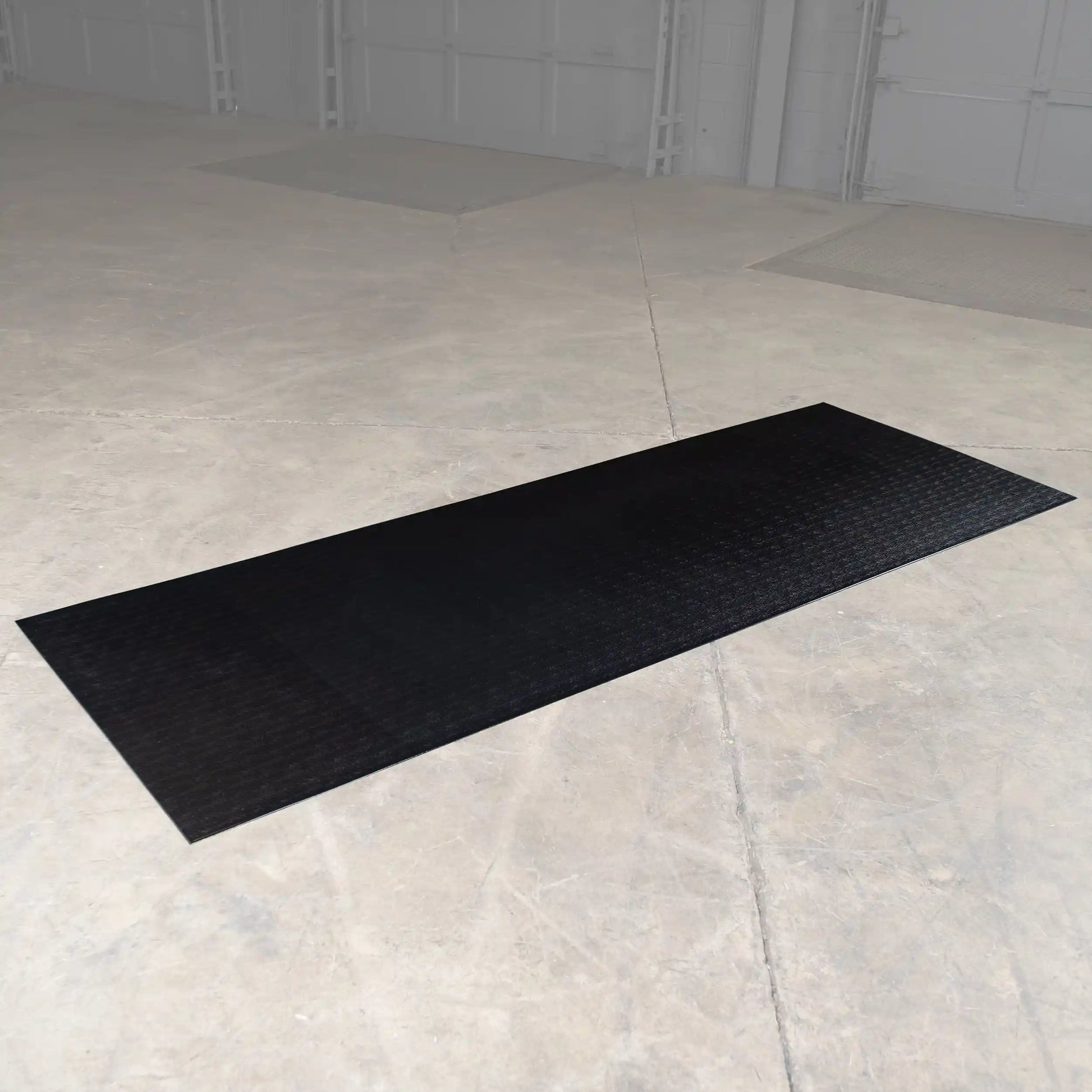 Black rubber parking mat on concrete garage floor.
